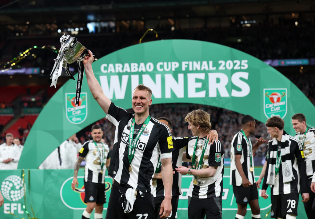Dan Burn holds the Carabao Cup trophy in the air after Newcastle United beat Liverpool at Wembley.