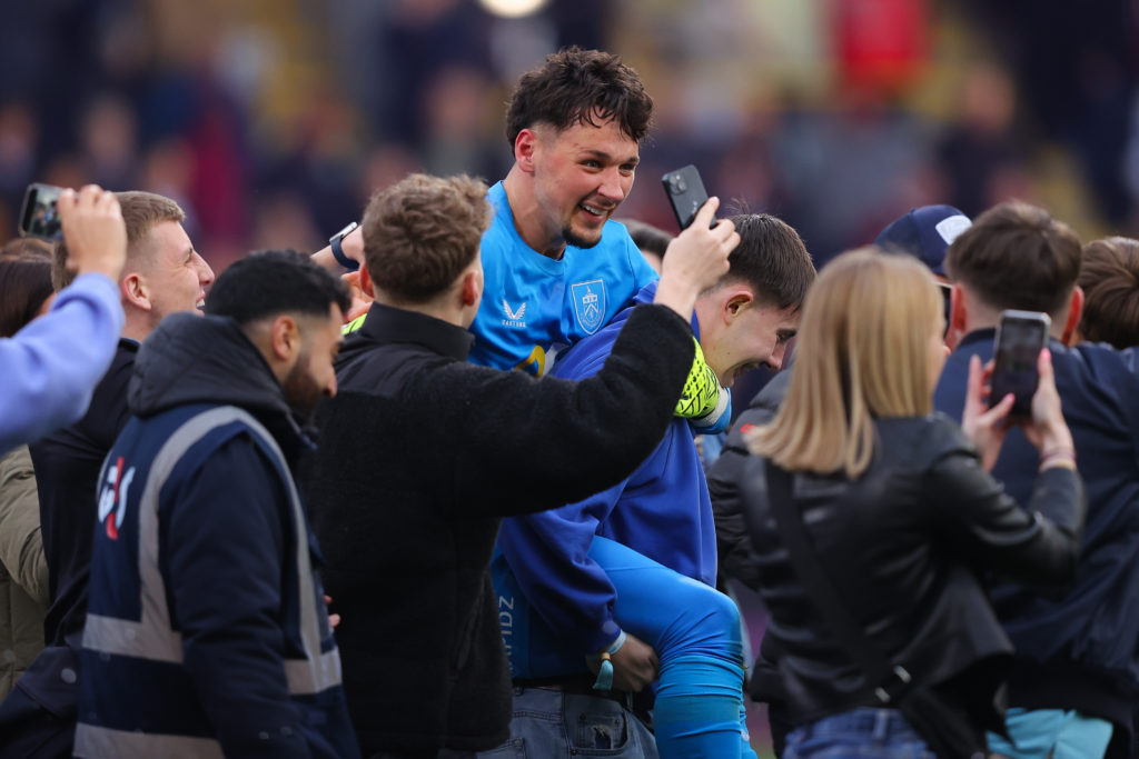 James Trafford is swarmed by supporters after Burnley earn promotion to the Premier League.