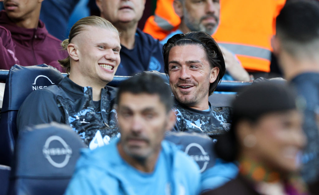 Jack Grealish sitting on the bench alongside Manchester City teammate Erling Haaland.