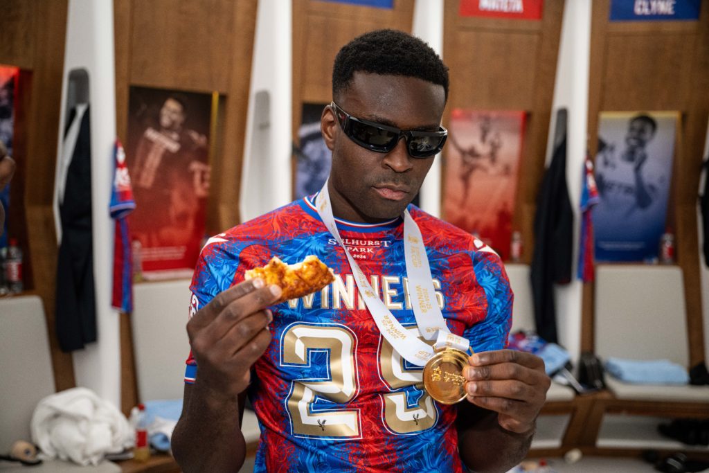 Marc Guehi eats pizza and poses with his medal after Crystal Palace beat Manchester City in the FA Cup final at Wembley.