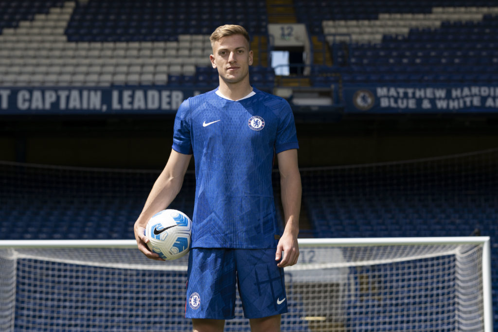 Liam Delap poses in a Chelsea shirt after signing for the club.