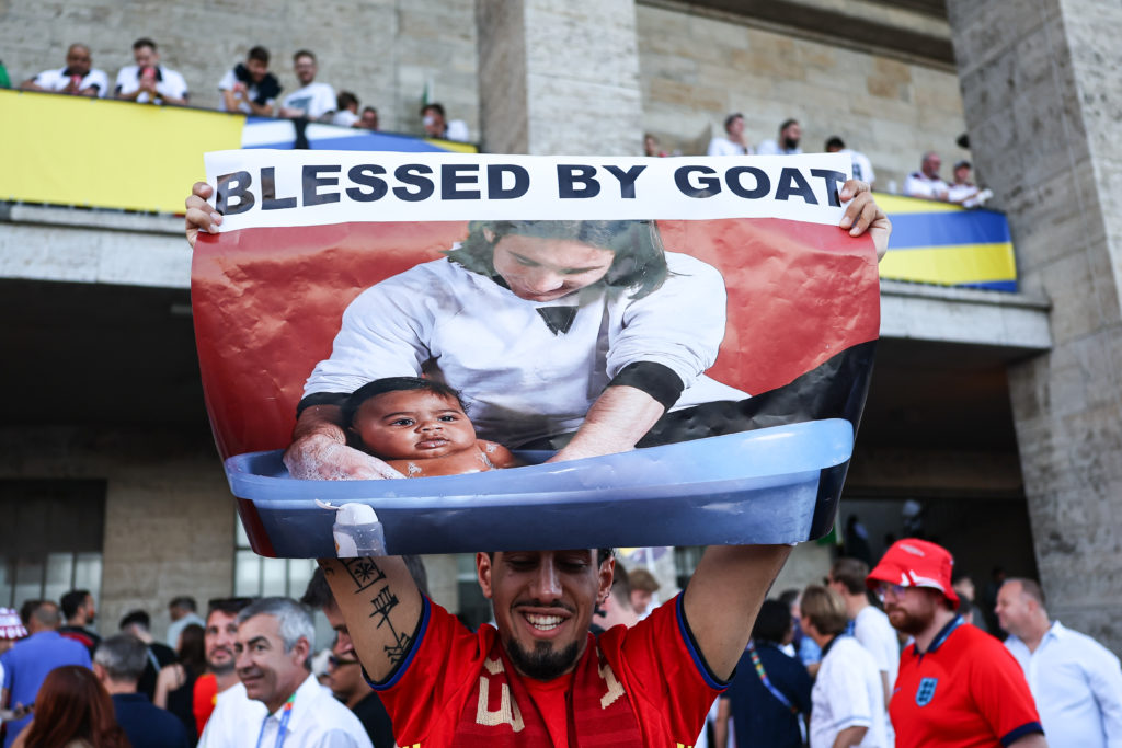 A Spain fan holds a post with a photograph of Messi bathing Yamal.