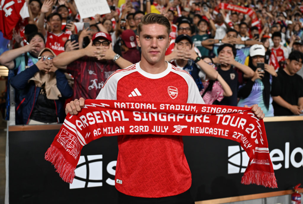 Viktor Gyokeres holds an Arsenal scarf in front of fans in Singapore.