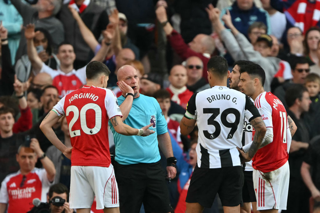 Simon Hooper talks on his head set as Jorginho and Bruno Guimaraes surround him.