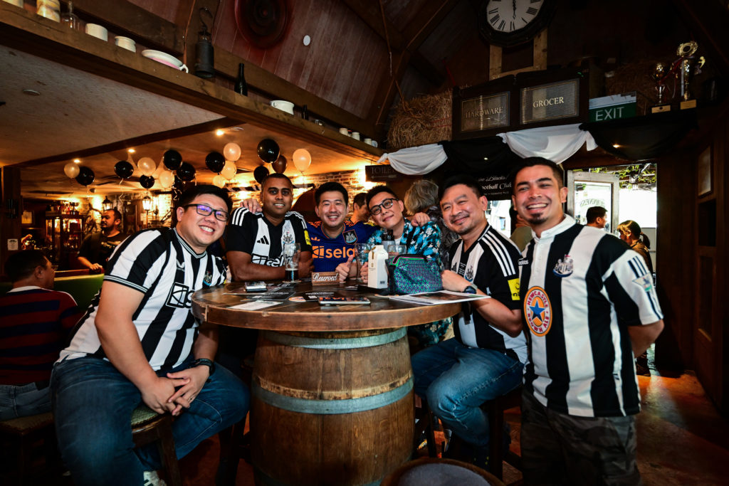 Newcastle Untied fans gather around a table.