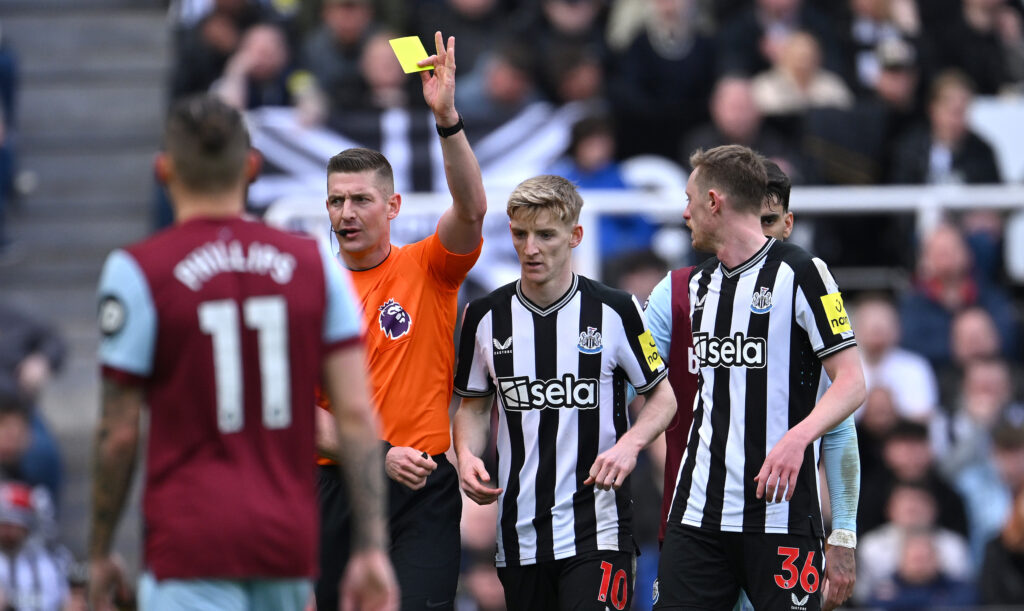 Rob Jones issues a yellow card to Anthony Gordon during Newcastle United vs West Ham.
