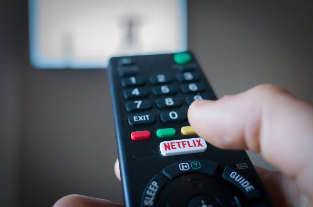 General photo of someone pressing the Netflix button on a television remote.