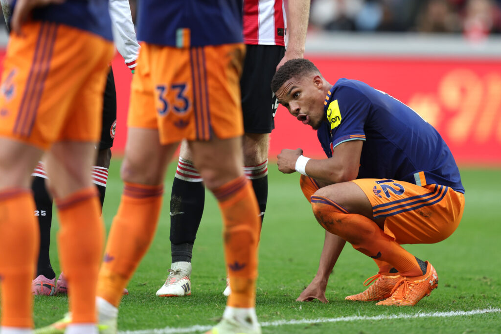 Malick Thiaw kneels down during Newcastle United's game against Brentford.