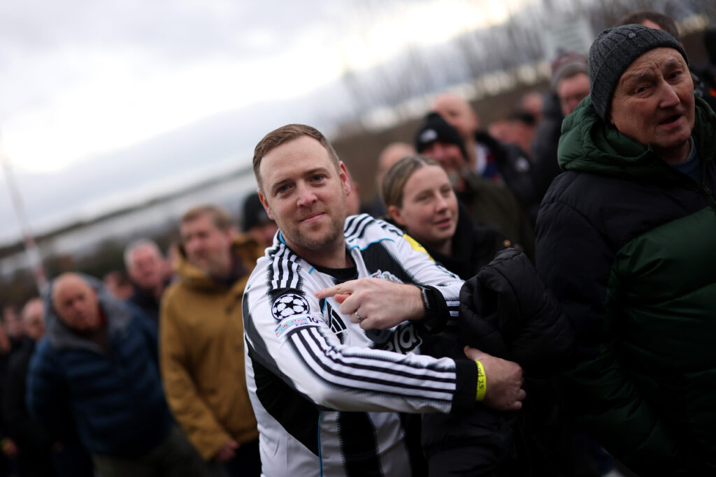 A Newcastle United fan points to the Champions League badge on the club's shirt ahead of the Tyne-Wear derby against Sunderland.